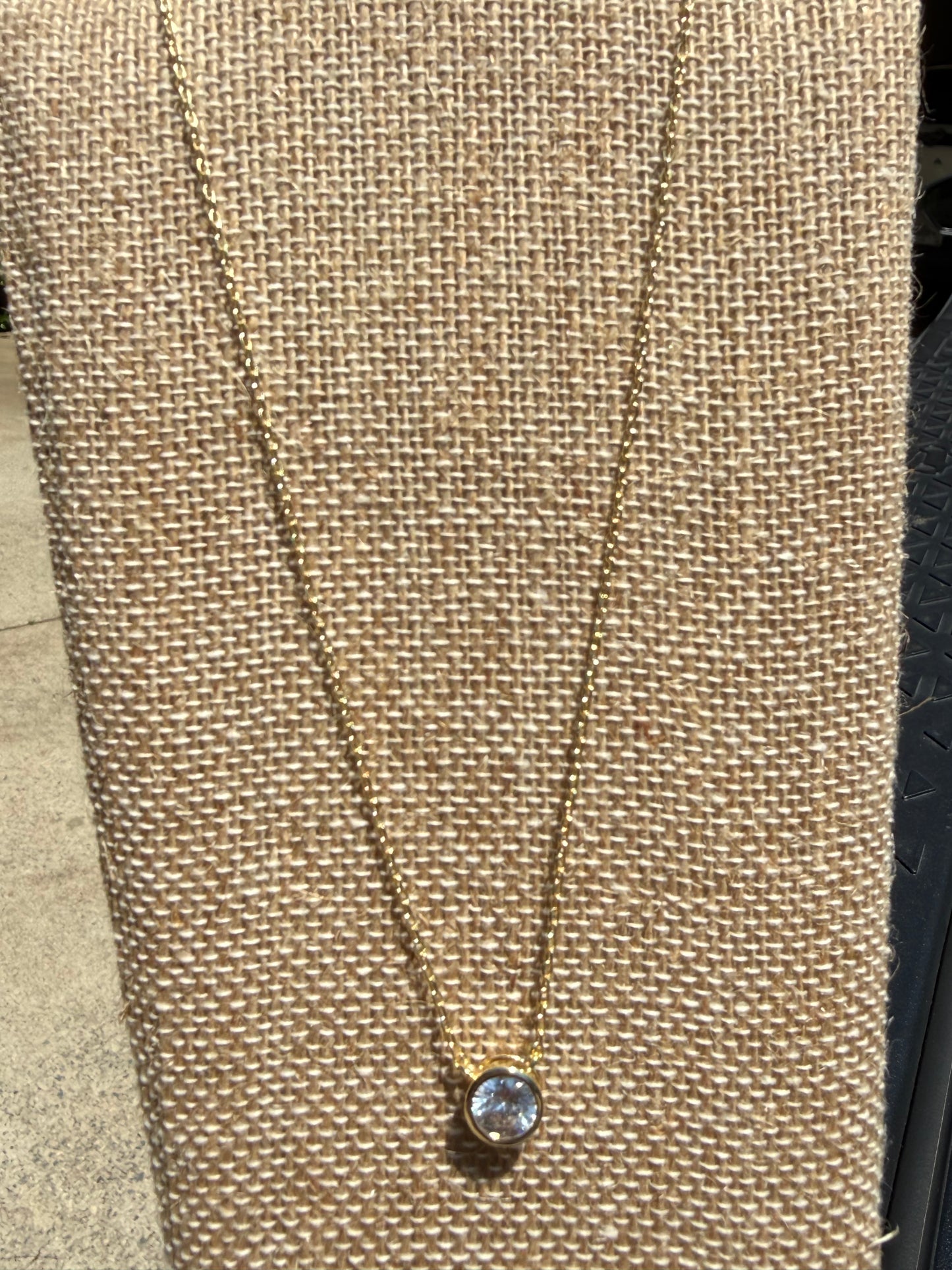 Dainty gold-tone necklace featuring a single crystal stone in a bezel setting, layering jewelry