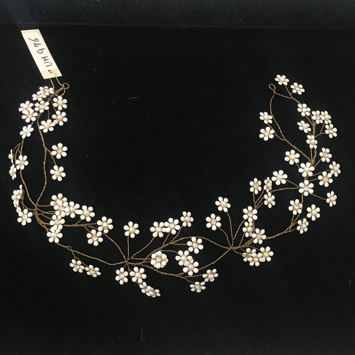 A floral bridal hair vine with small white blossoms and crystal centers on a bronze wire.
