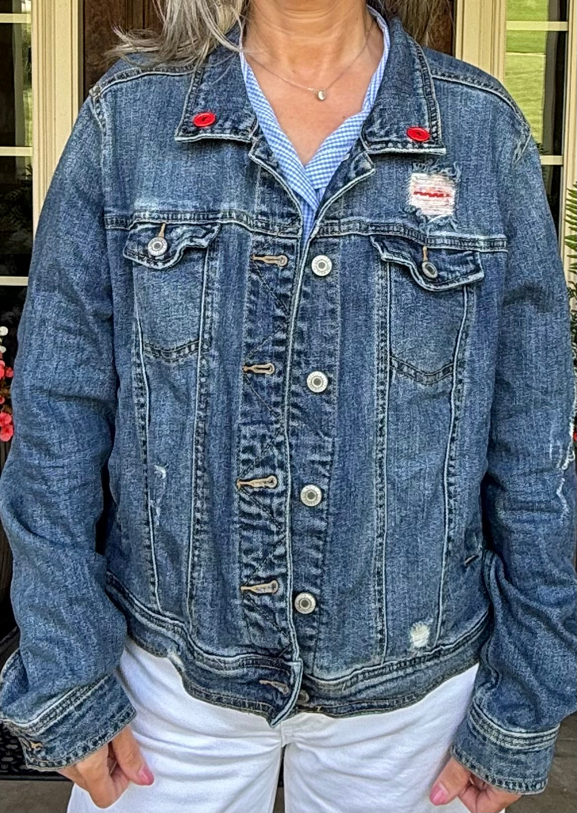 Front of an upcycled Mossimo denim jacket with red button accents at the collar at Dover Grace Boutique in Watkinsville, Georgia.
