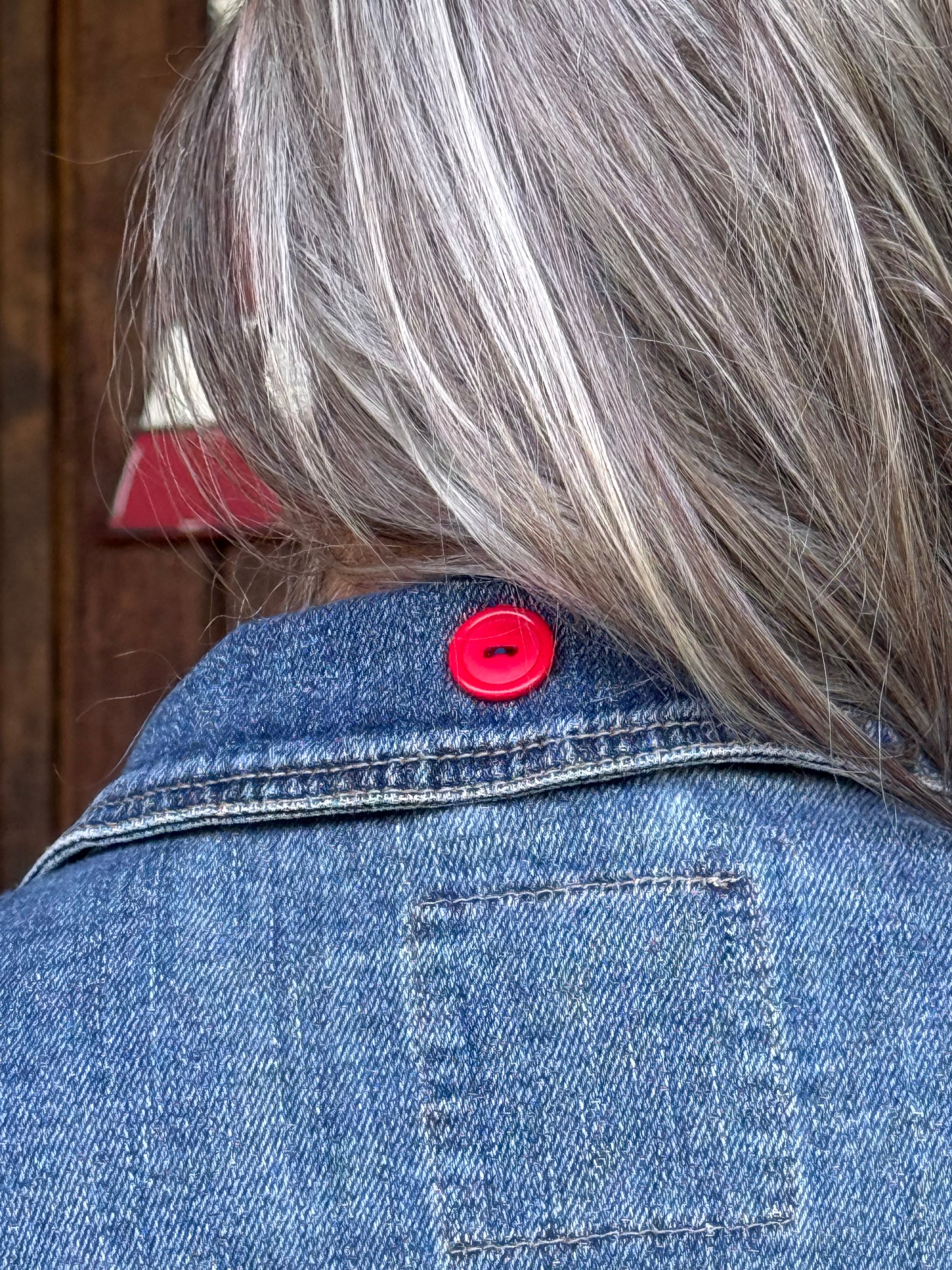 Red button accent on the back collar of an upcycled Mossimo denim jacket at Dover Grace Boutique in Watkinsville, Georgia.