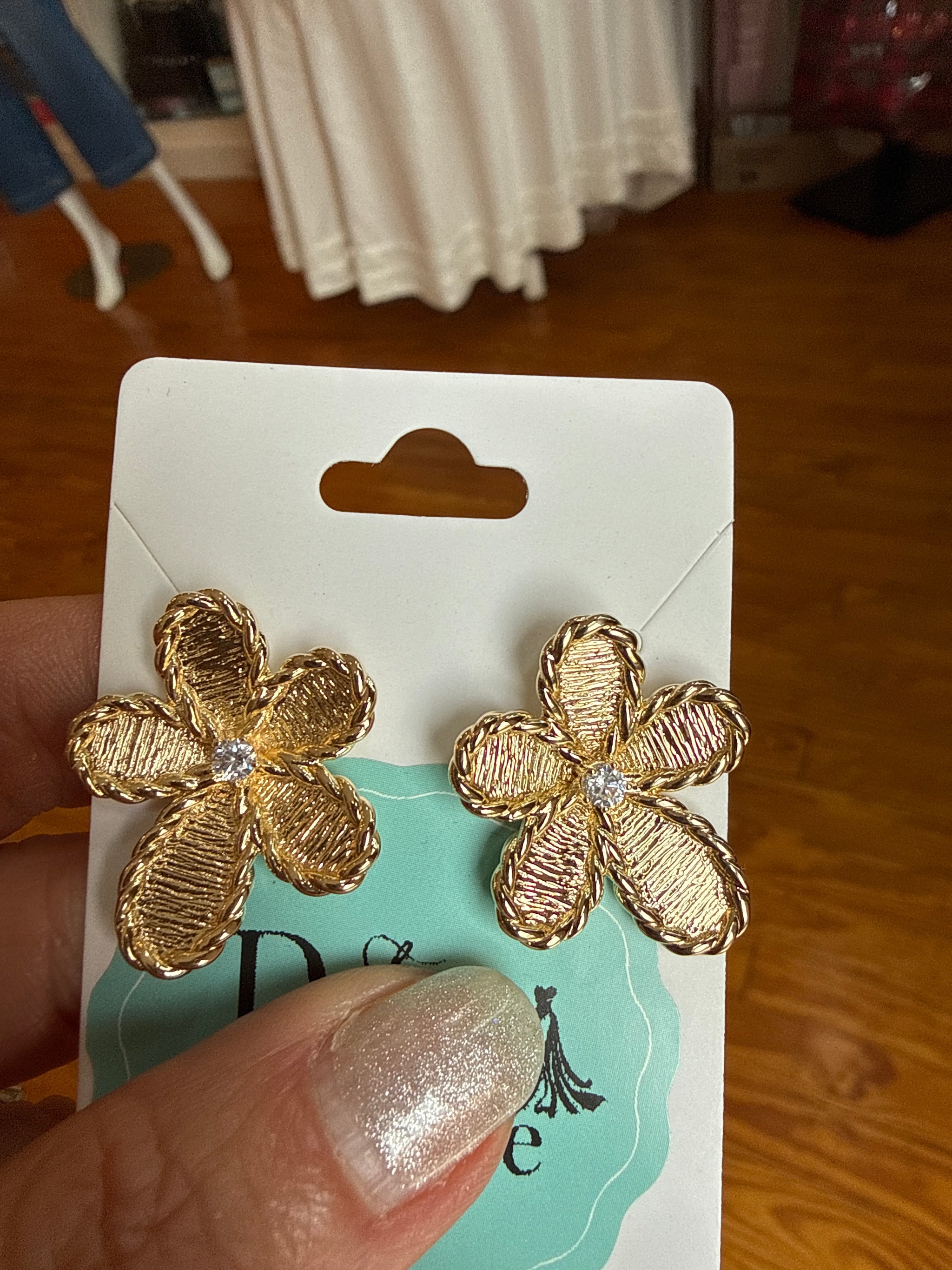 Gold tone four-petal flower stud earrings with ribbed textured petals, twisted rope border, and sparkling crystal center,