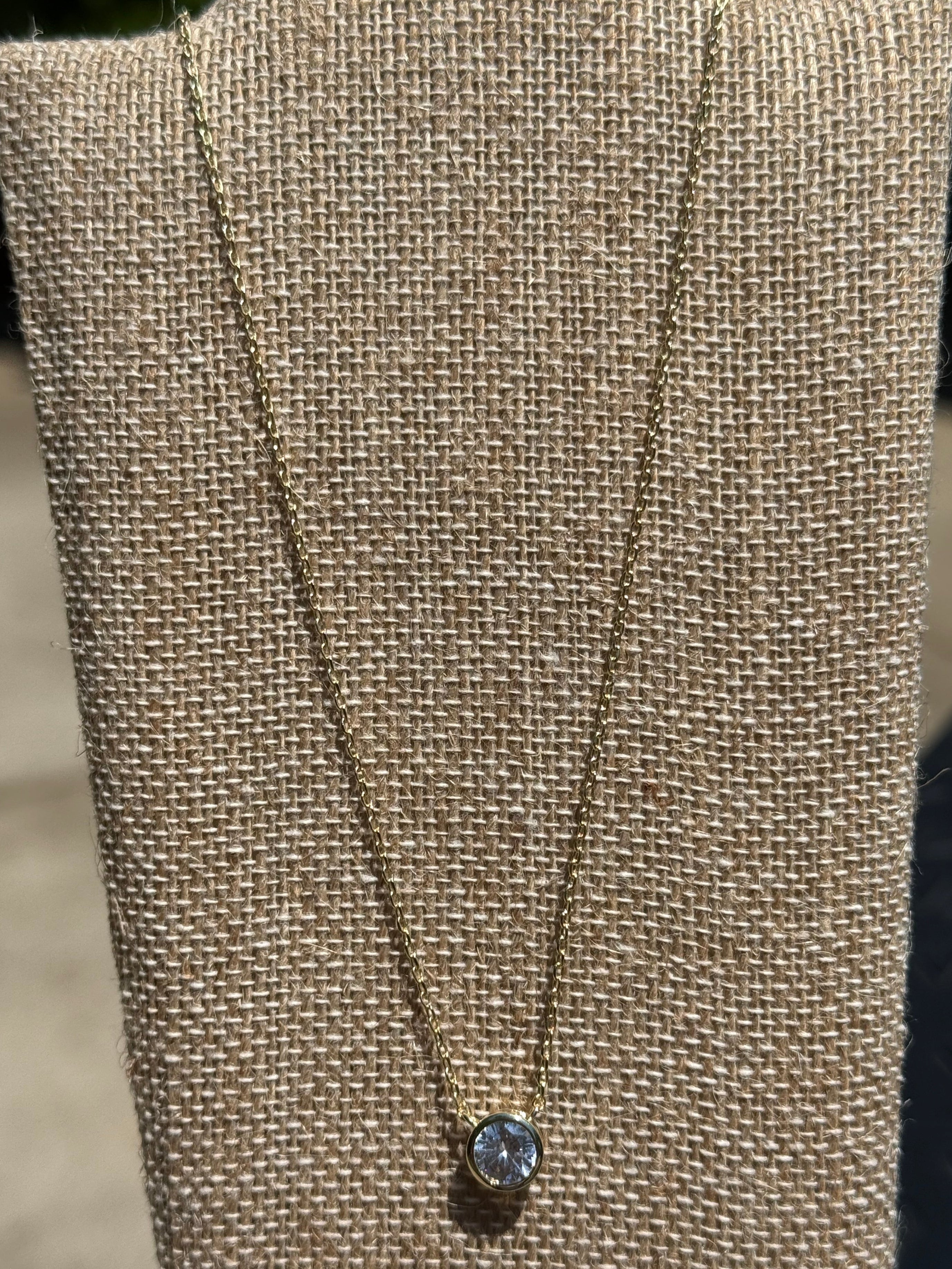 Dainty gold-tone necklace featuring a single crystal stone in a bezel setting, layering jewelry