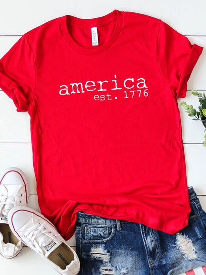 A bright red, short-sleeved t-shirt featuring the text "america est. 1776" in white, distressed typewriter-style lettering across the chest.