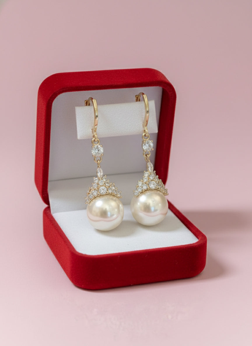 Pearl earrings in a red jewelry box on a pink background