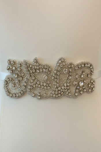 Decorative belt with intricate silver beading on a plain background