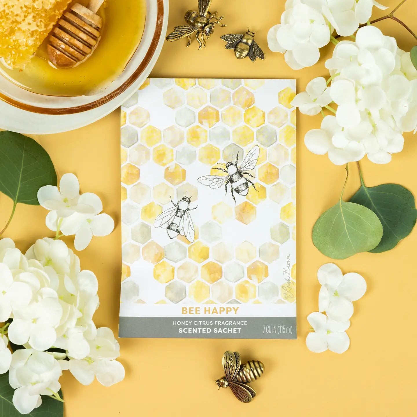 Scented sachet with bee design surrounded by flowers and honeycomb on a yellow background