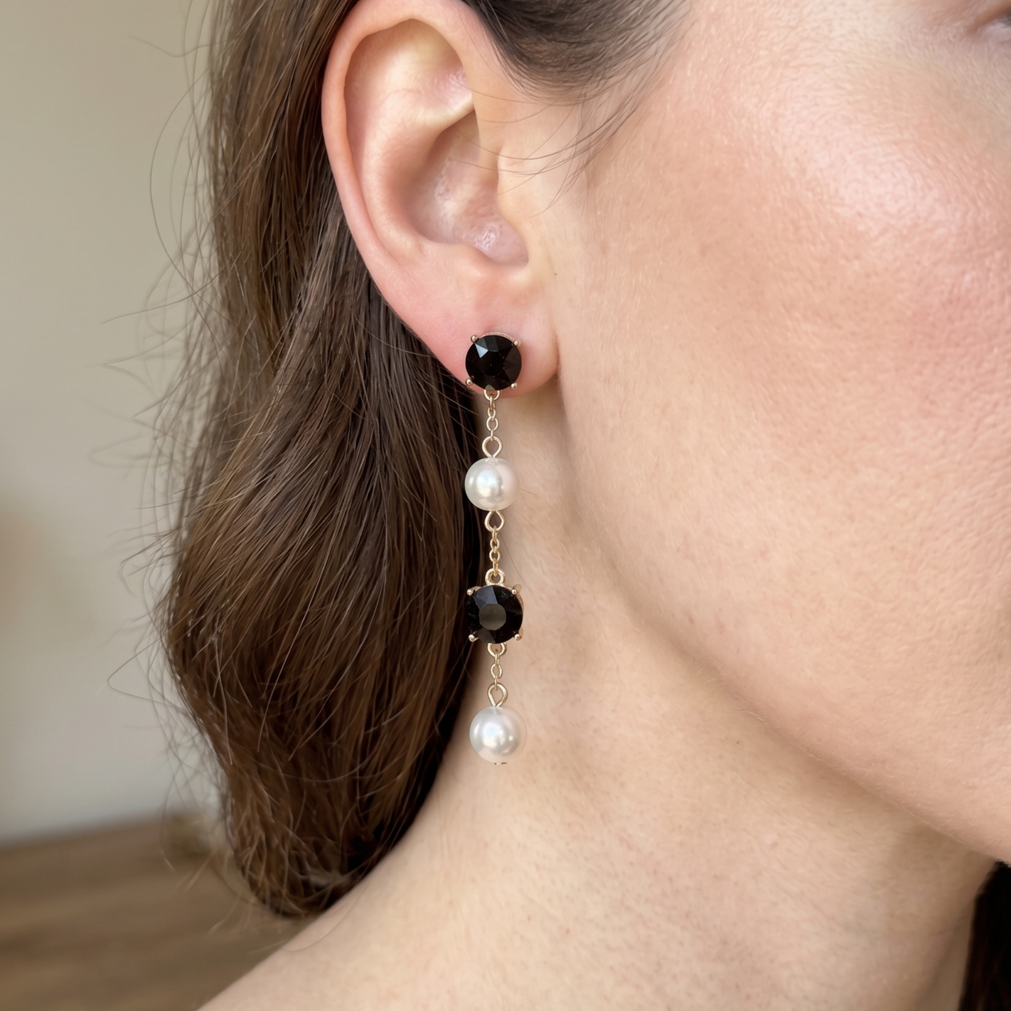 Gold-tone earrings with alternating black crystal and white pearl drops in a vertical cascade.