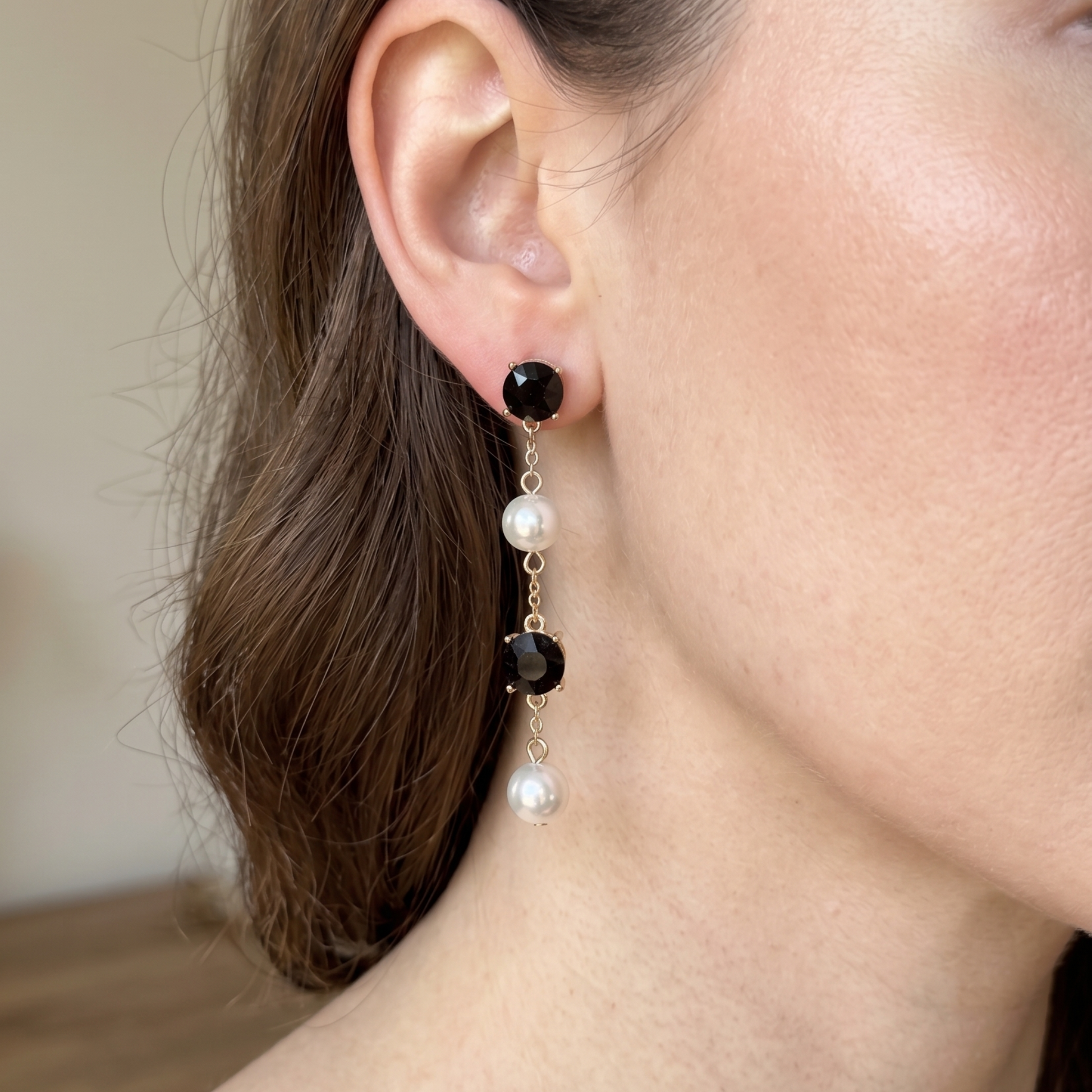 Gold-tone earrings with alternating black crystal and white pearl drops in a vertical cascade.