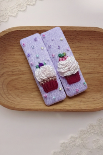 A pair of lavender textured hair clips featuring hand-embroidered cupcakes with white frosting and colorful sprinkle accents.