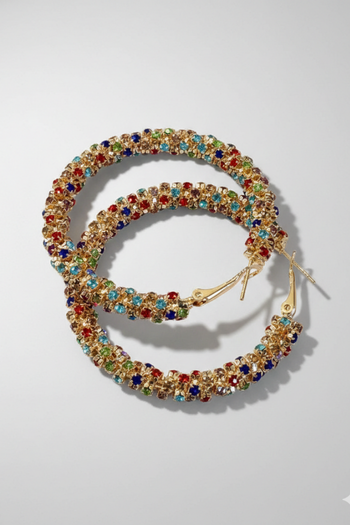 Chunky gold-toned hoop earrings pave-set with vibrant multicolored crystals on a neutral grey background.