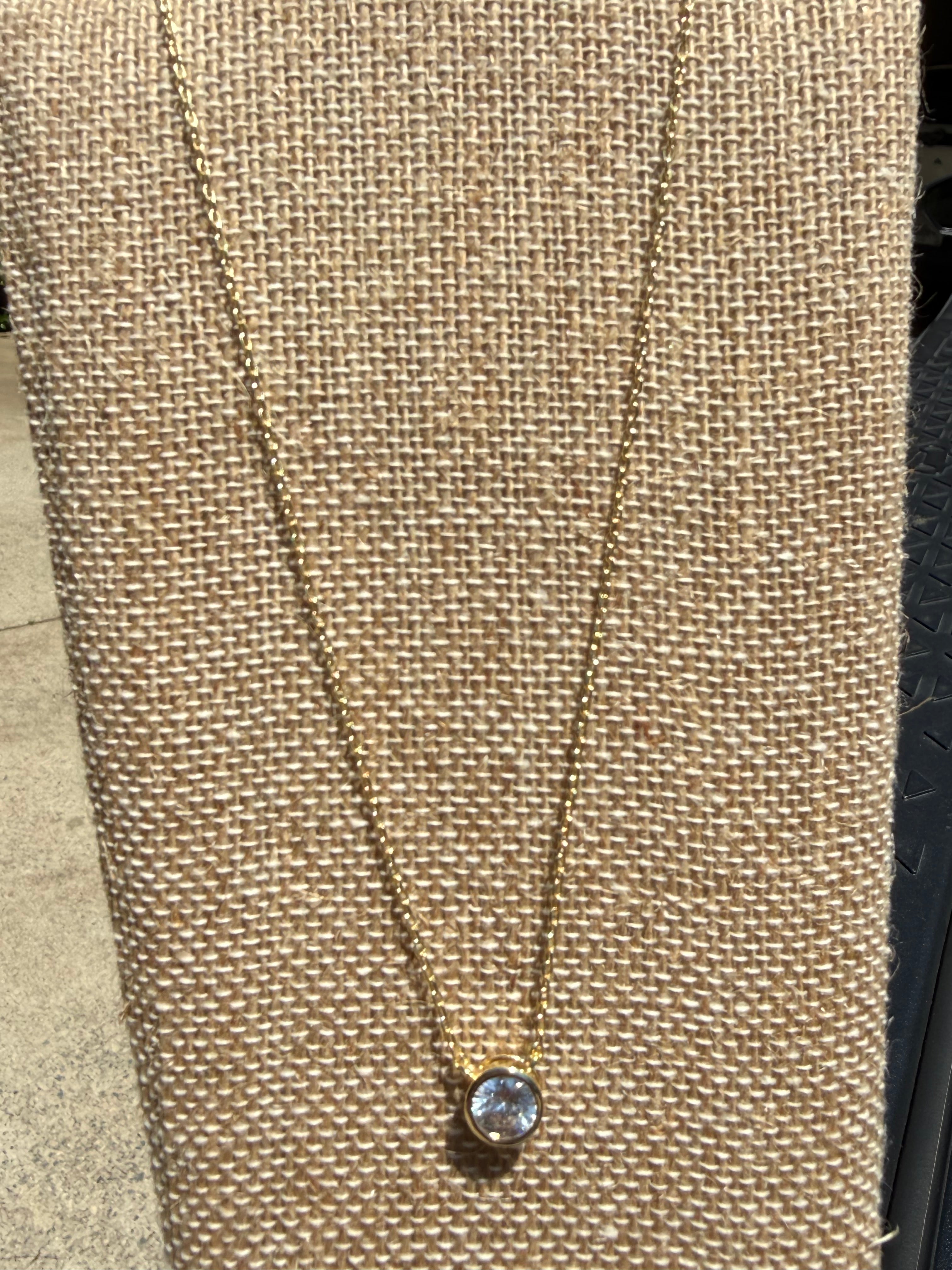 Dainty gold-tone necklace featuring a single crystal stone in a bezel setting, layering jewelry
