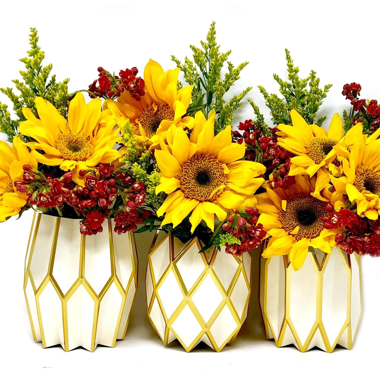 Three geometric-patterned vases with sunflowers and red flowers on a white background