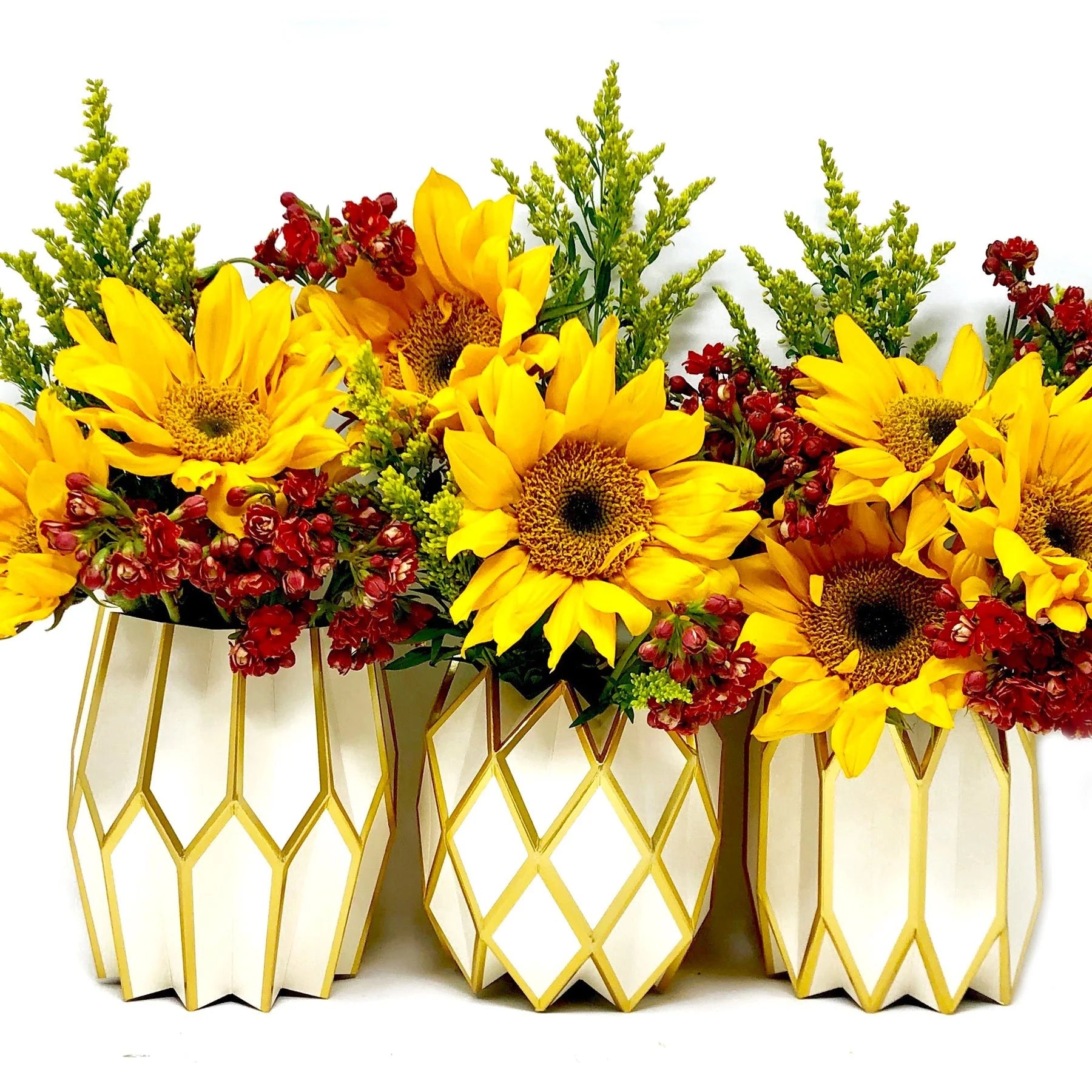 Three geometric-patterned vases with sunflowers and red flowers on a white background
