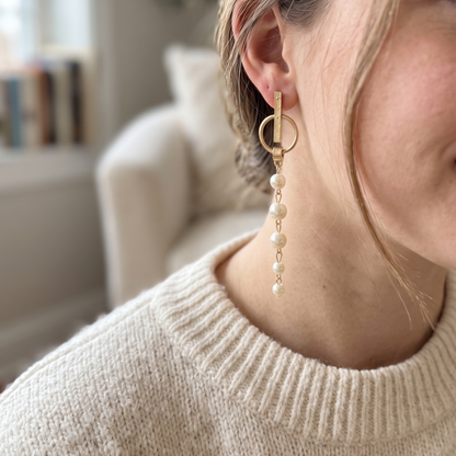 Gold-tone earrings with a horizontal bar and graduated pearl drop on each side.