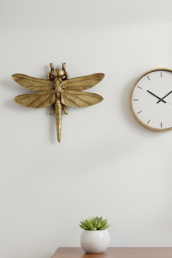 A decorative, metallic gold dragonfly figurine with textured wings and a detailed body