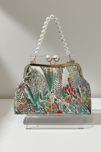 Floral patterned handbag with pearl handle on a stand against a neutral background