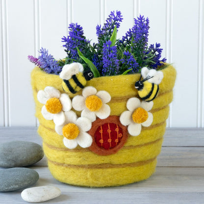 A yellow felt pot shaped like a beehive decorated with white daisies and bees on a white background.