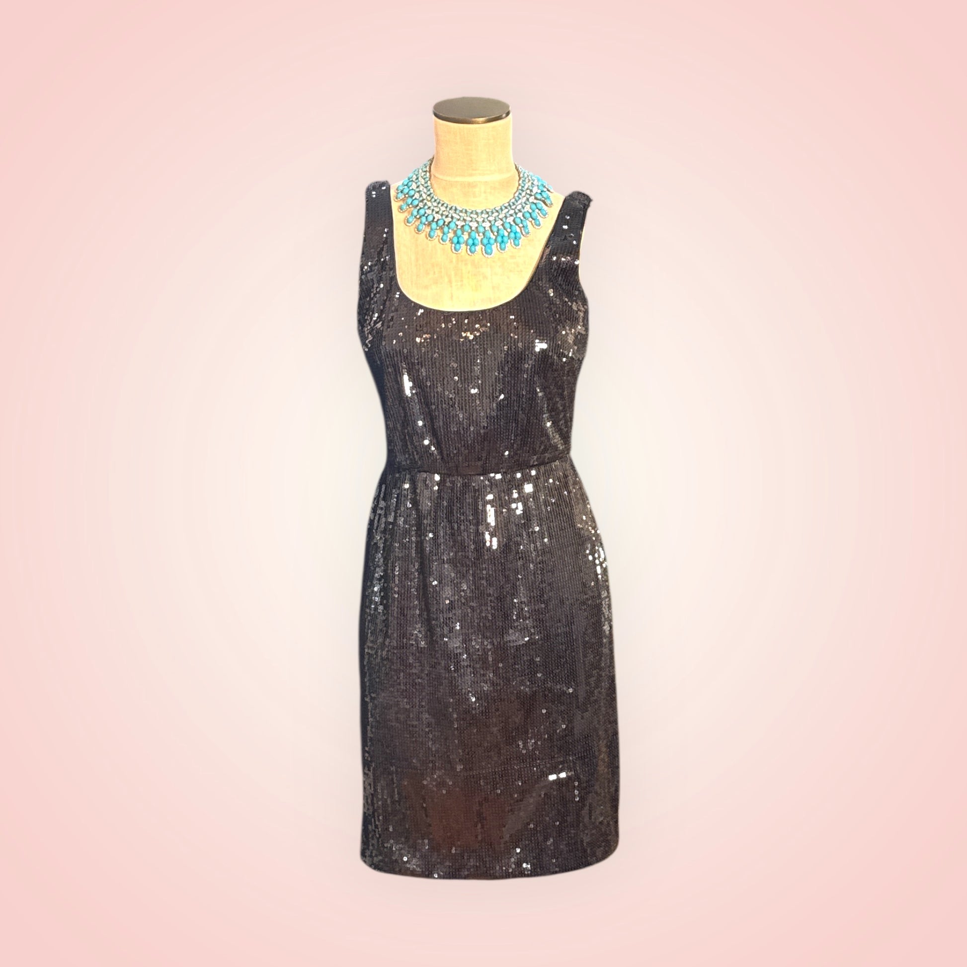 Black sequin dress on a mannequin with a pink gradient background