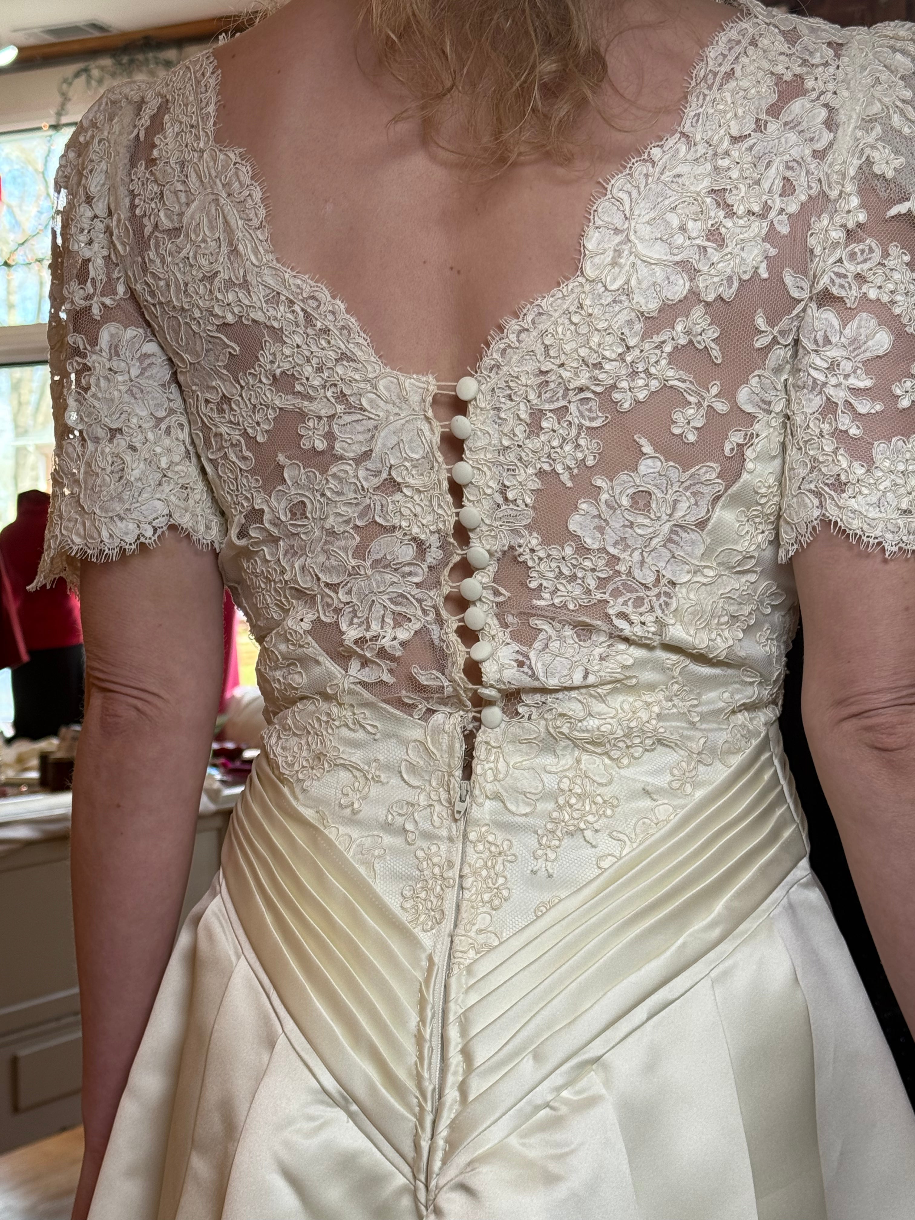 Close-up of a lace-trimmed wedding dress with a button detail.