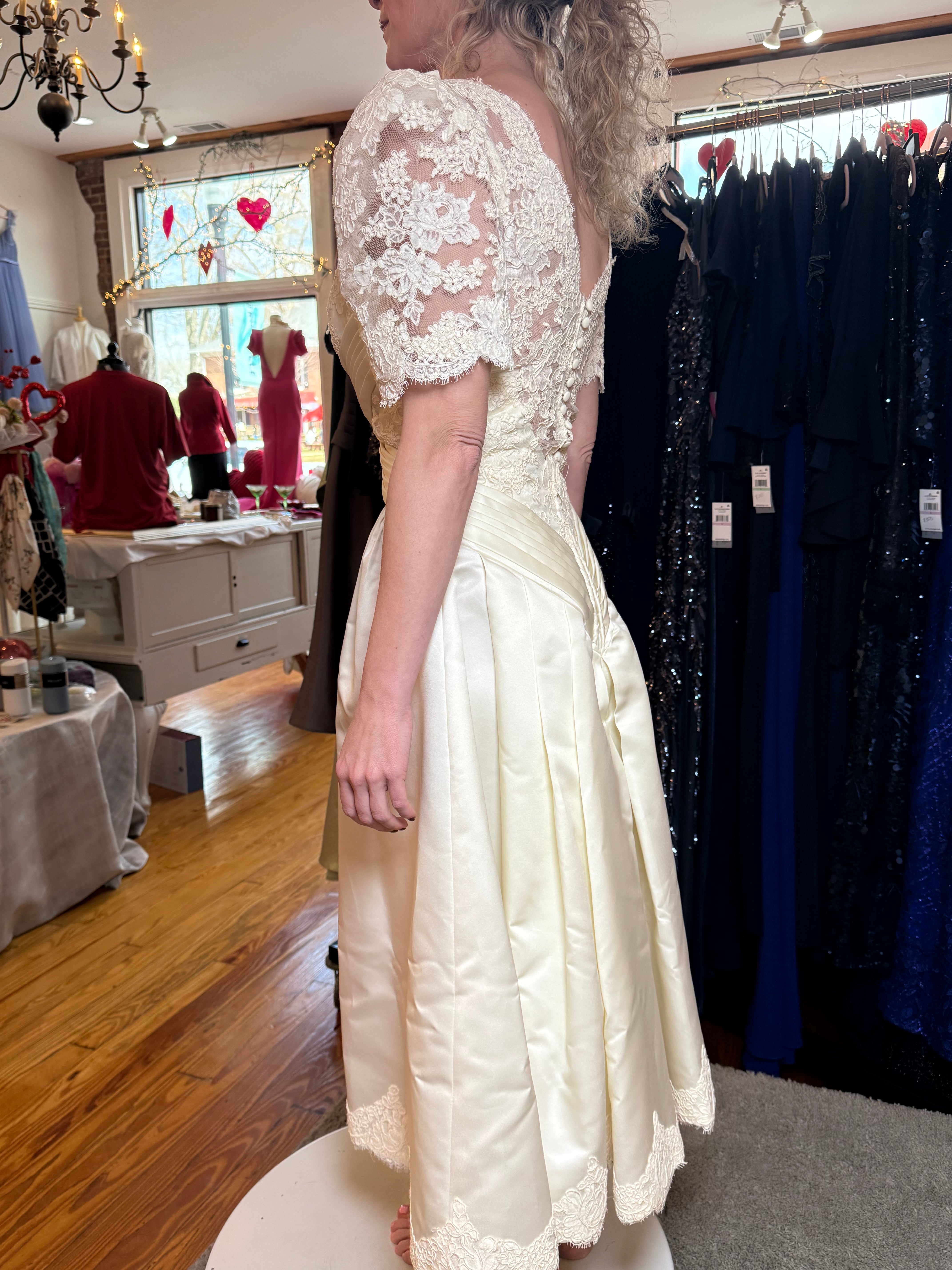 Person wearing a white lace dress in a clothing store.