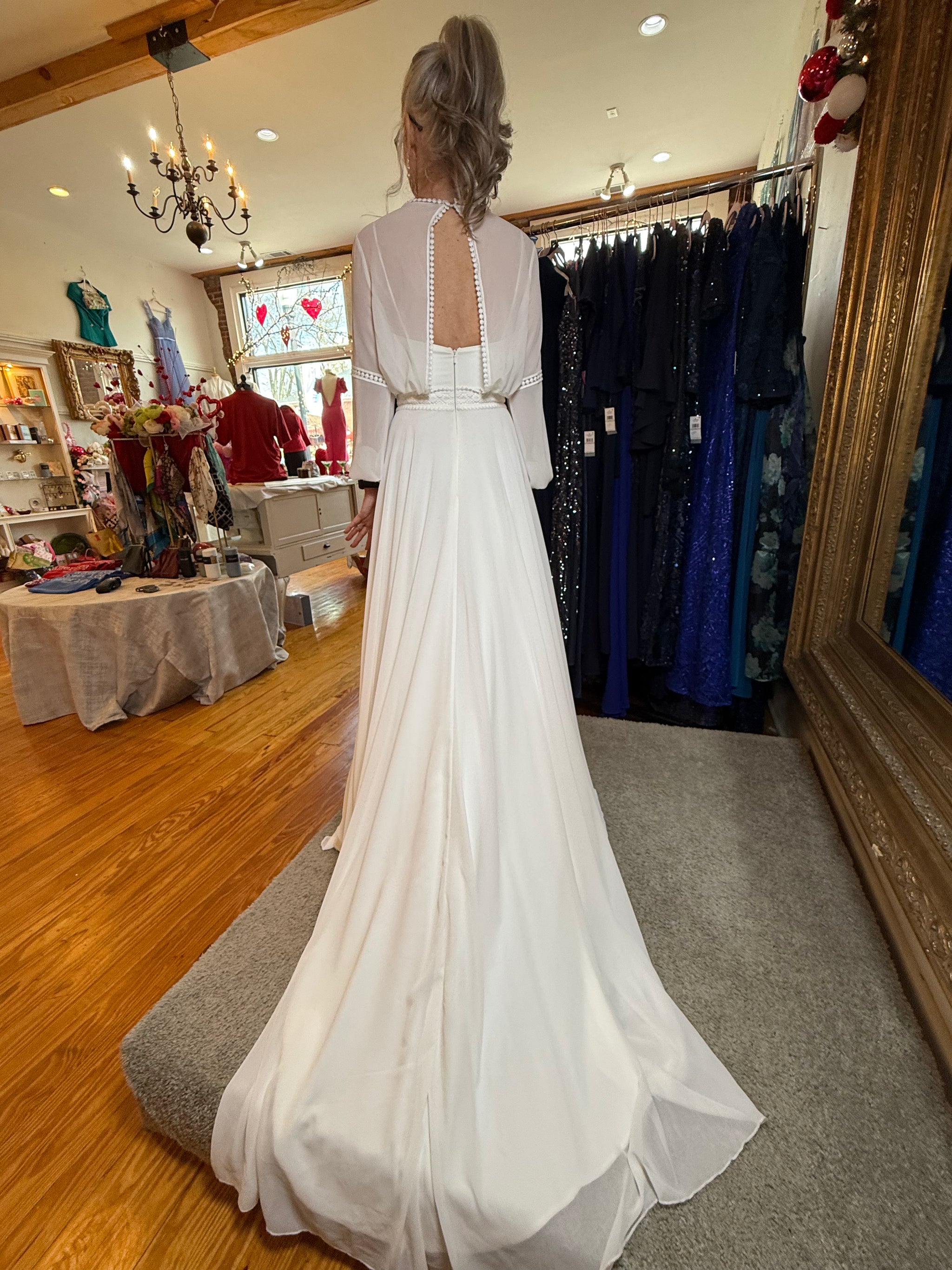 Woman in a white dress standing in a store with clothing racks and decor.