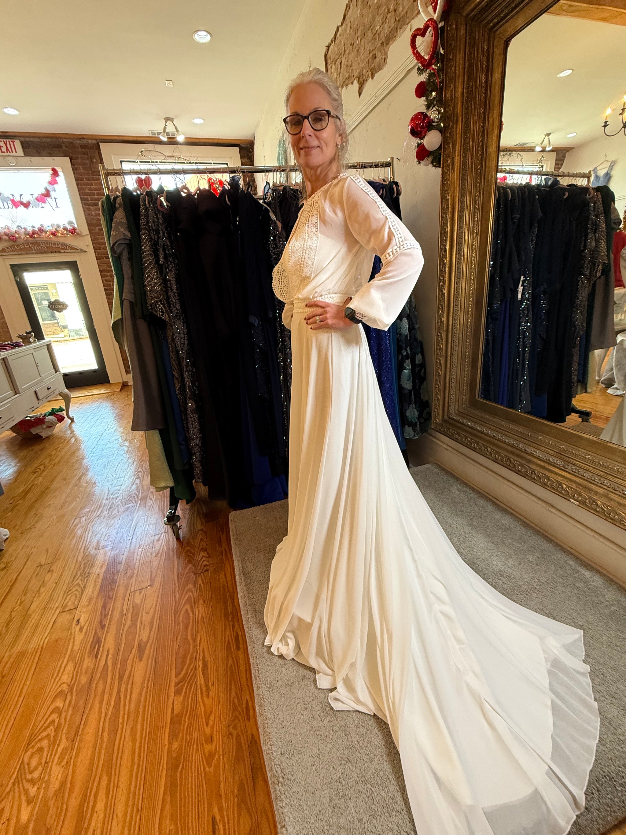 Woman in a white dress standing in front of a mirror in a clothing store.