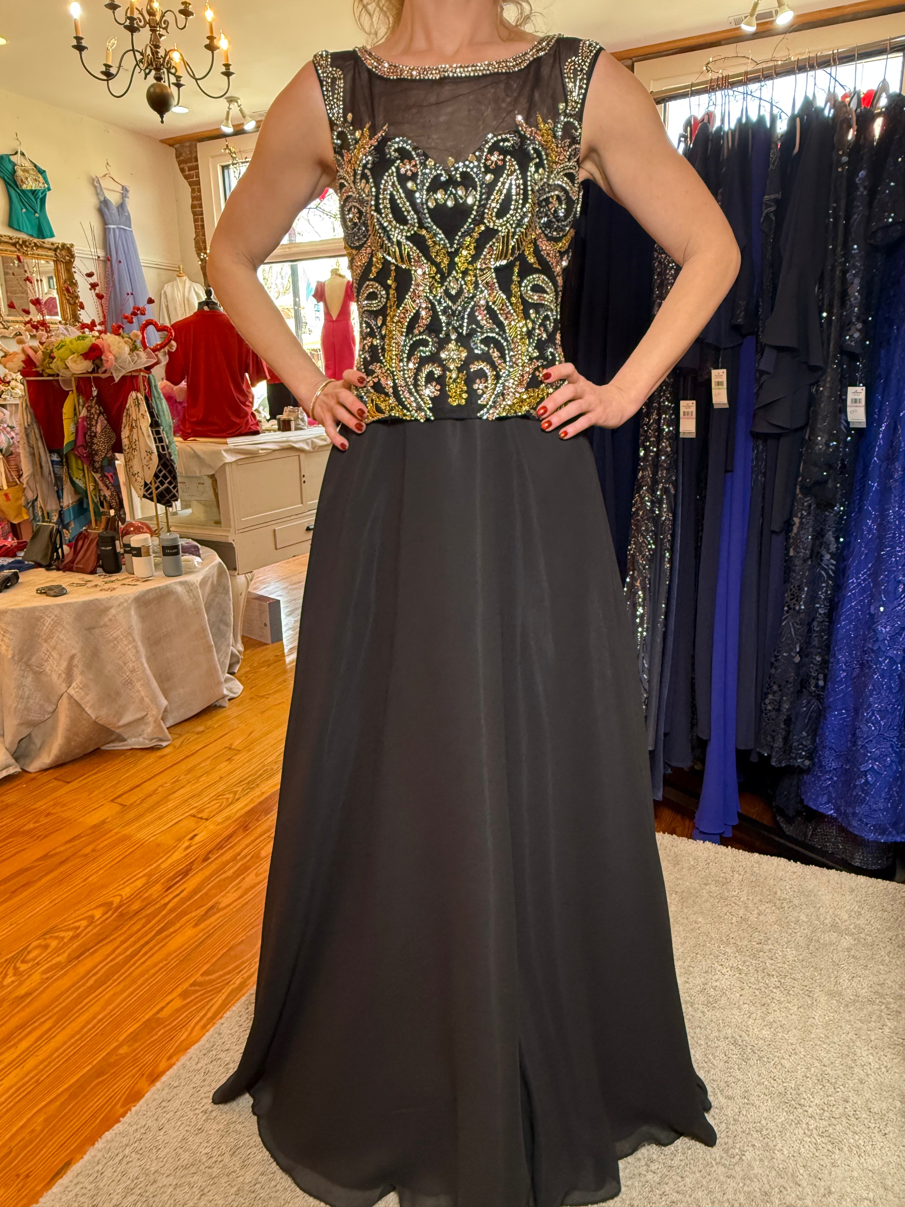 Woman wearing a black evening gown with gold embroidery in a store setting.