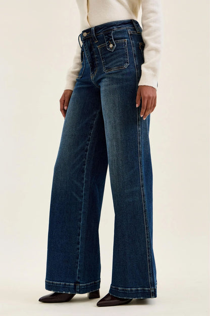 Side view of Judy Blue Retro Wide Leg jeans showing generous wide-leg opening, released hem, deep fade indigo wash, and front patch pocket with vintage tab closure detail