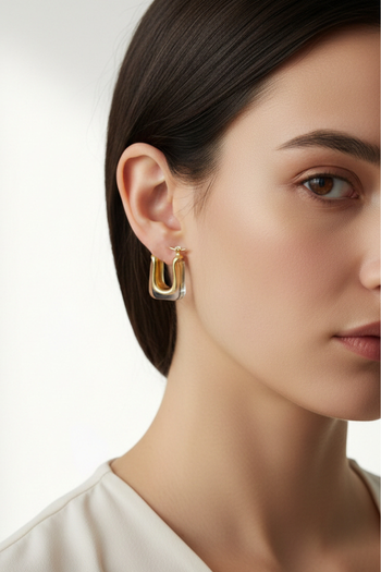 Minimalist gold U-shaped hoop earrings encased in clear rectangular resin on a pale ceramic dish.