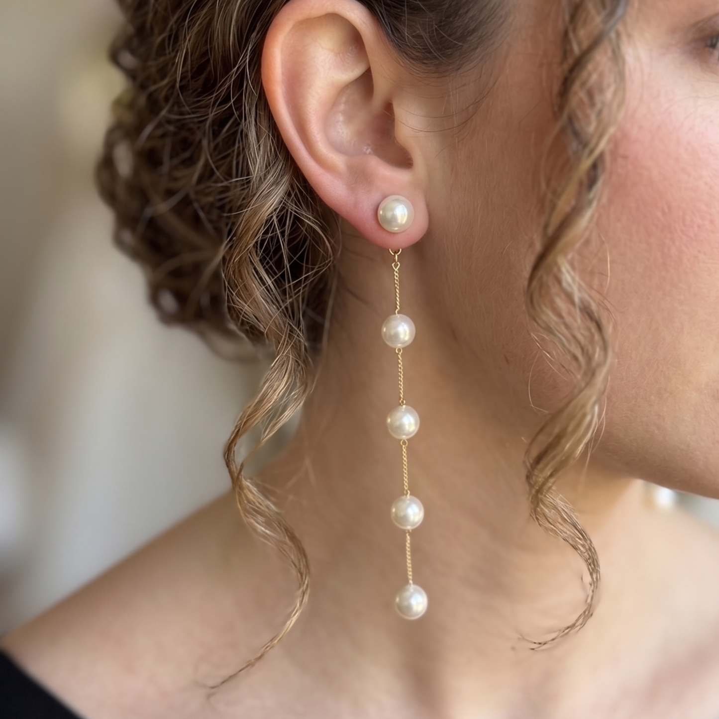 Long gold-tone chain earrings with a single hanging pearl drop on each side.