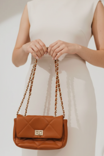 Tan quilted faux-leather handbag with a gold turn-lock closure and gold chain-link straps interwoven with matching leather.