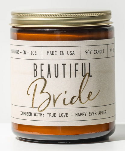 An amber glass soy candle with a gold lid and a cream label featuring "Beautiful Bride" in black and gold script.