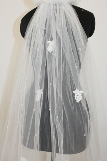 White wedding veil with floral appliqués on a black mannequin.