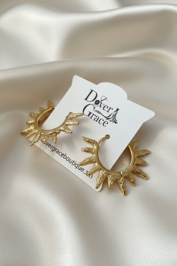 Gold-tone hoop earrings with textured flame-like spikes radiating outward, displayed on a white card.