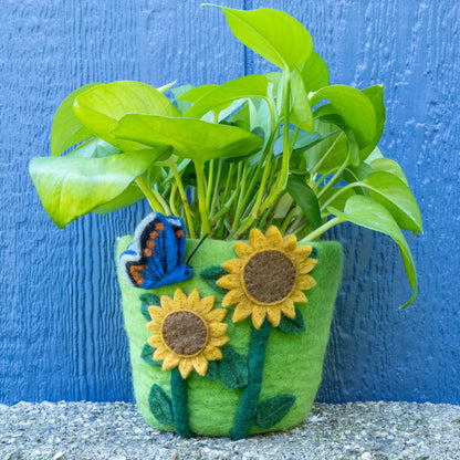 A green felt pot decorated with yellow sunflowers and a blue butterfly on a white background.