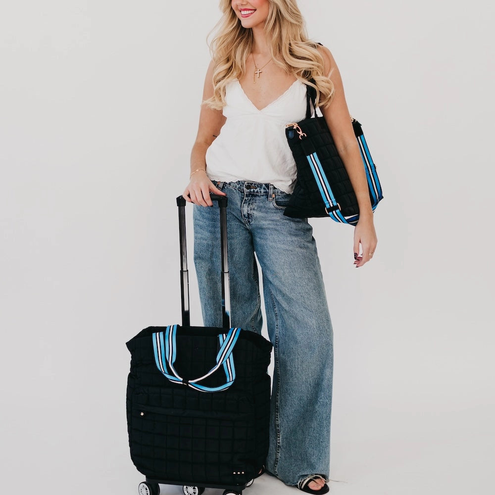A black quilted rolling tote bag and matching quilted shoulder tote, both featuring distinctive blue and white striped handles and gold hardware.
