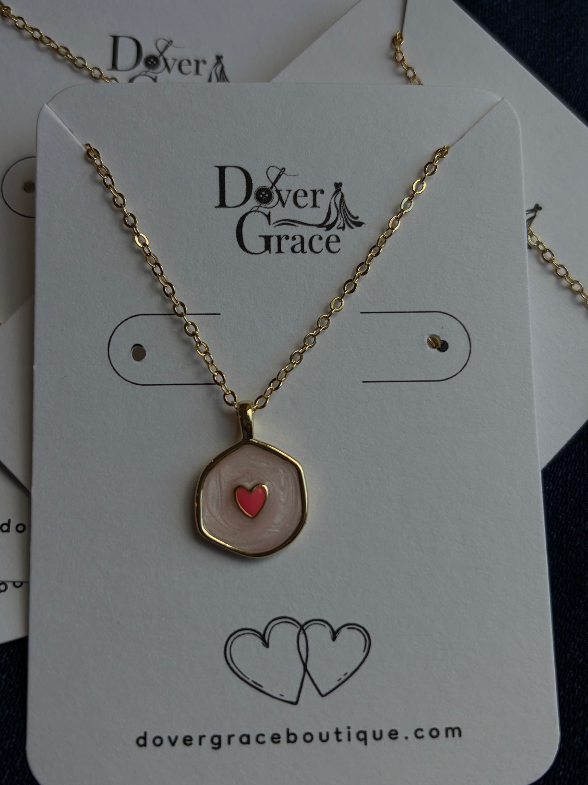 Close-up of blush enamel hexagon heart pendant at Dover Grace Boutique in Watkinsville, Georgia.