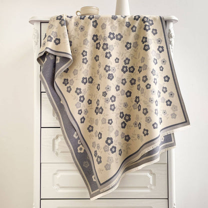 Blue and ivory floral jacquard wrap draped over a white cabinet, showing its reverse and fringe.