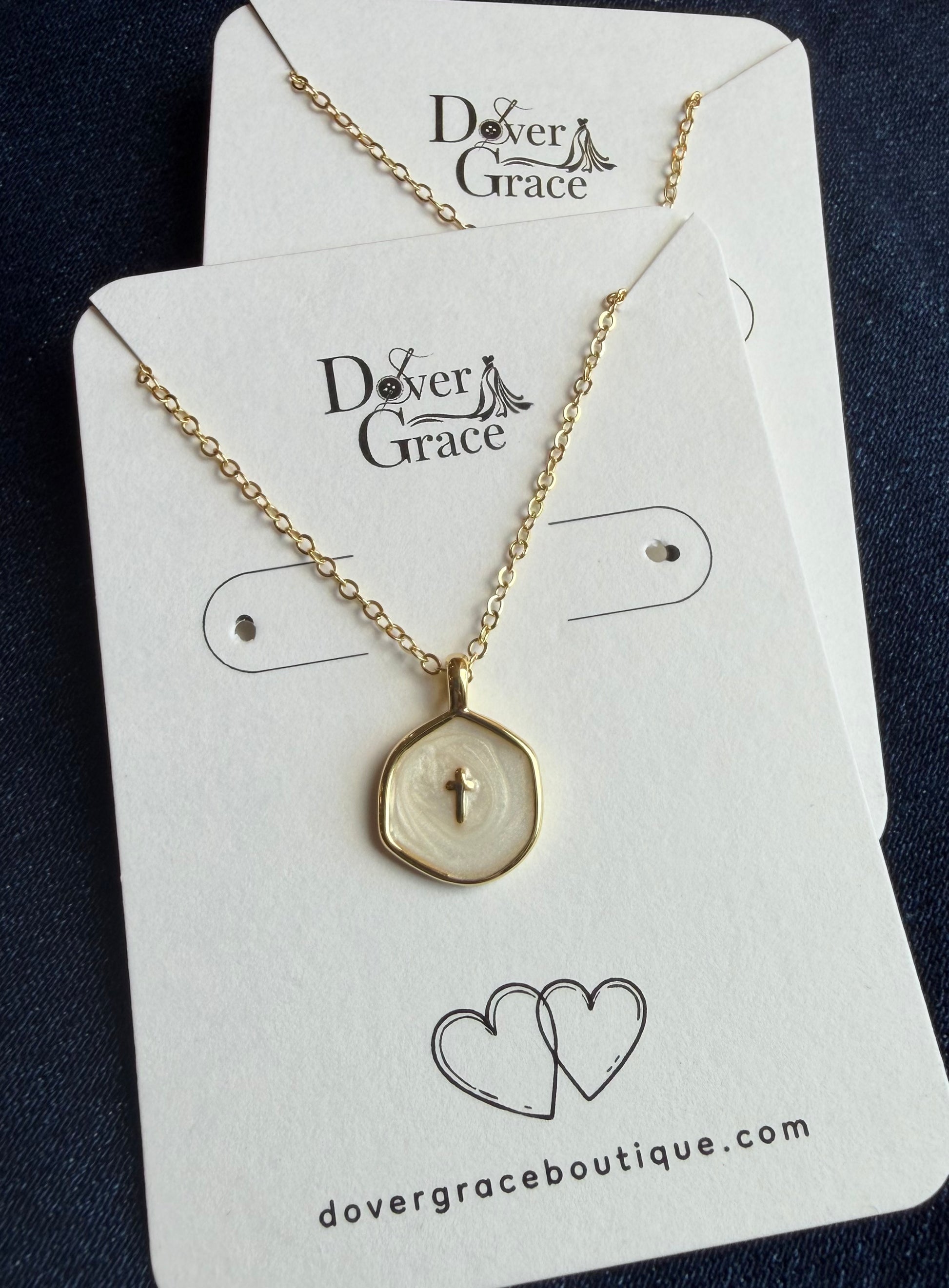 Gold cross necklace with white enamel pendant at Dover Grace Boutique in Watkinsville, Georgia.