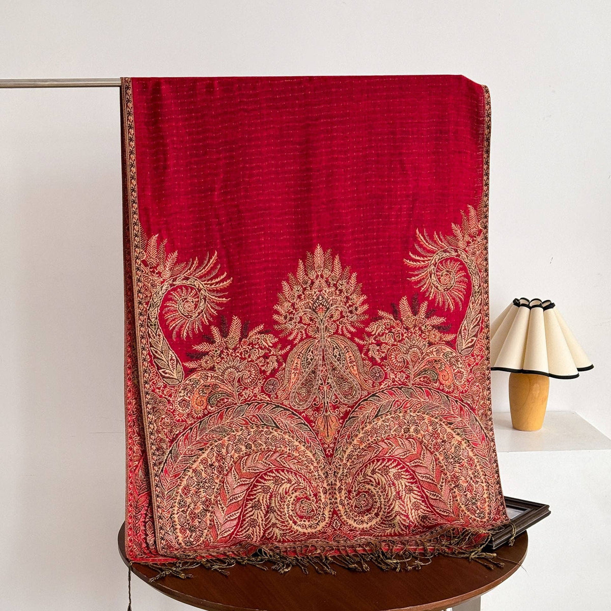 Red woven scarf with ornate gold floral and paisley motifs, a patterned border and fringe.