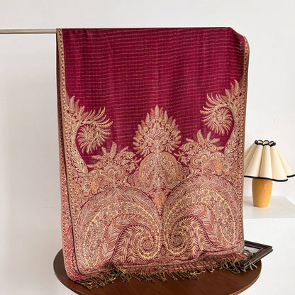 Hanging red heritage-print wrap showing detailed gold paisley motifs and twisted fringe.