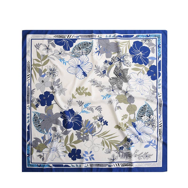 Square ivory shawl with blue and gray flowers, green leaves and a blue border, laid flat.