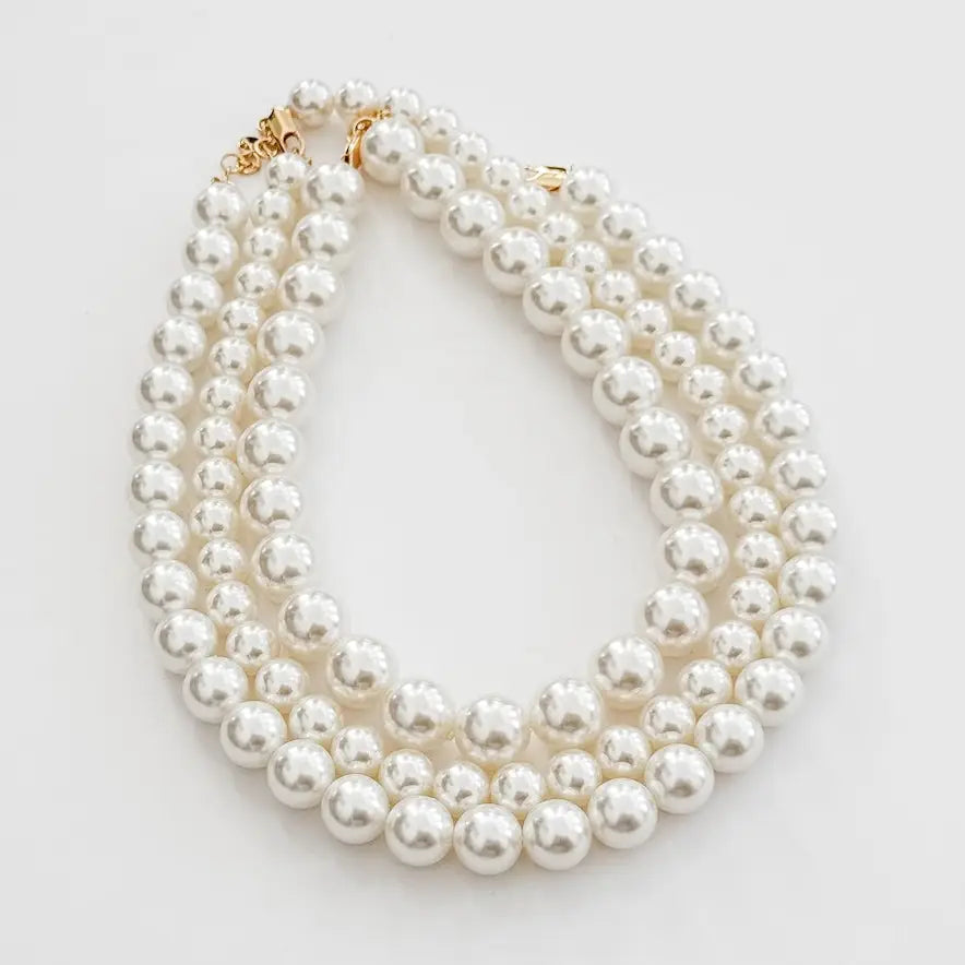 Multiple strands of pearls on a light gray background