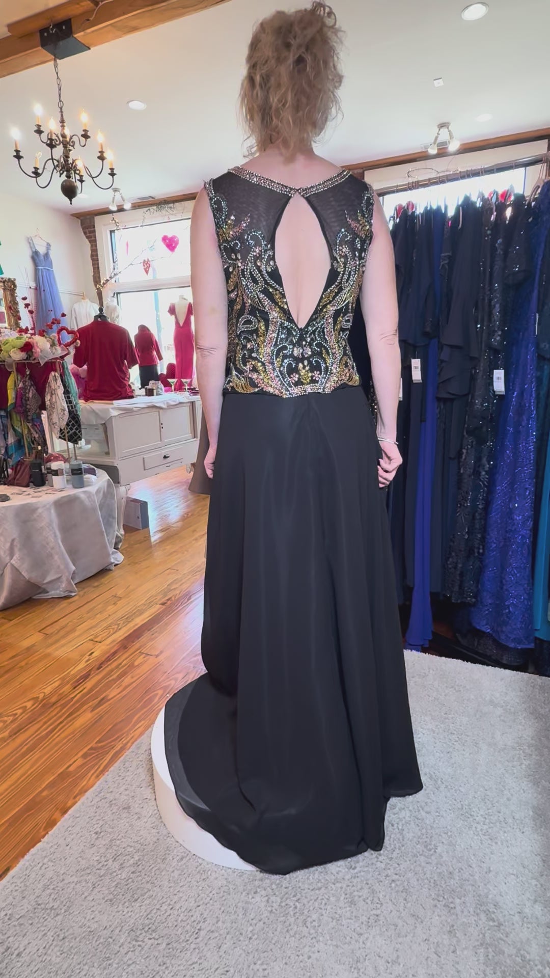 Woman wearing a black evening gown with a patterned top in a clothing store.