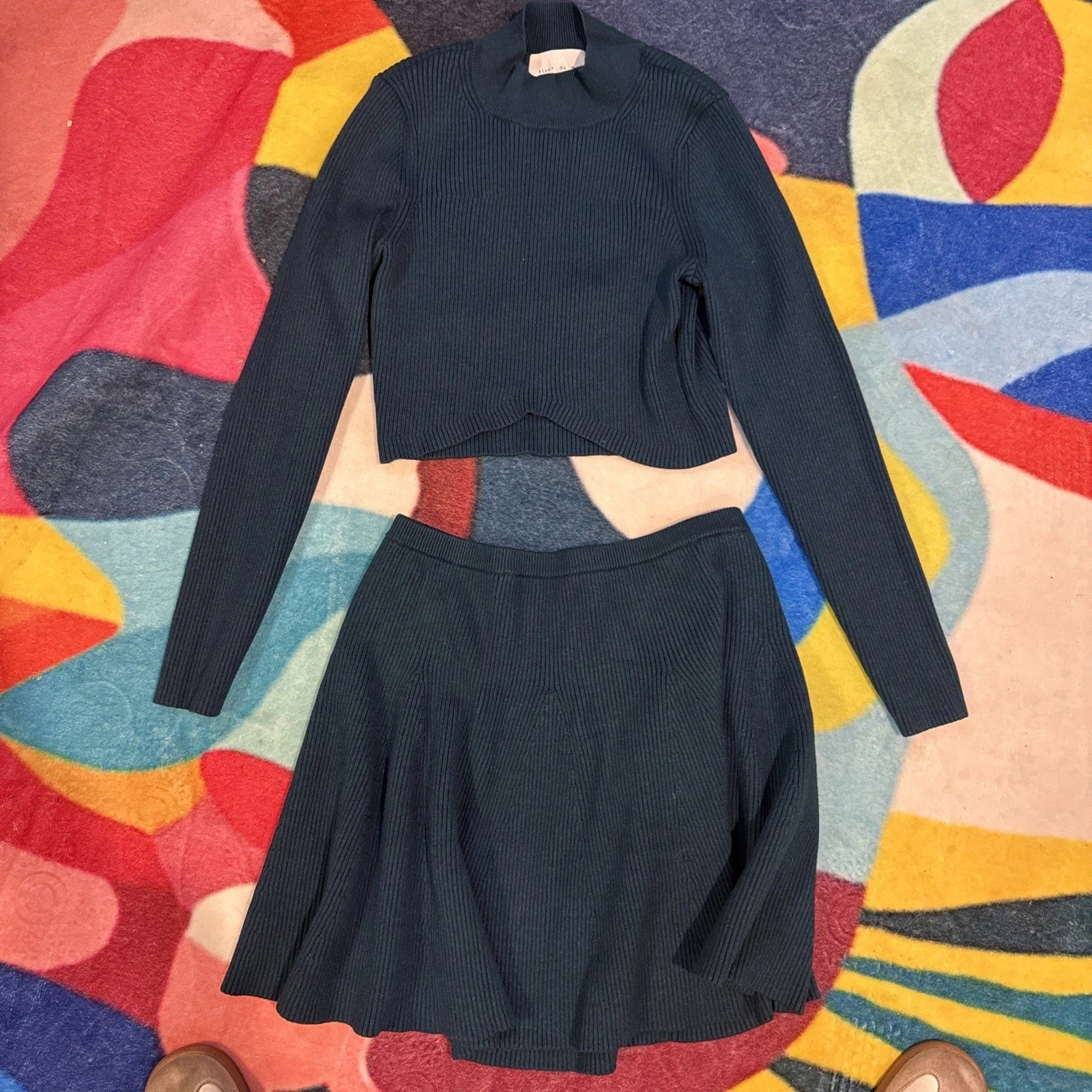 Black ribbed sweater and skirt set on a colorful abstract-patterned surface