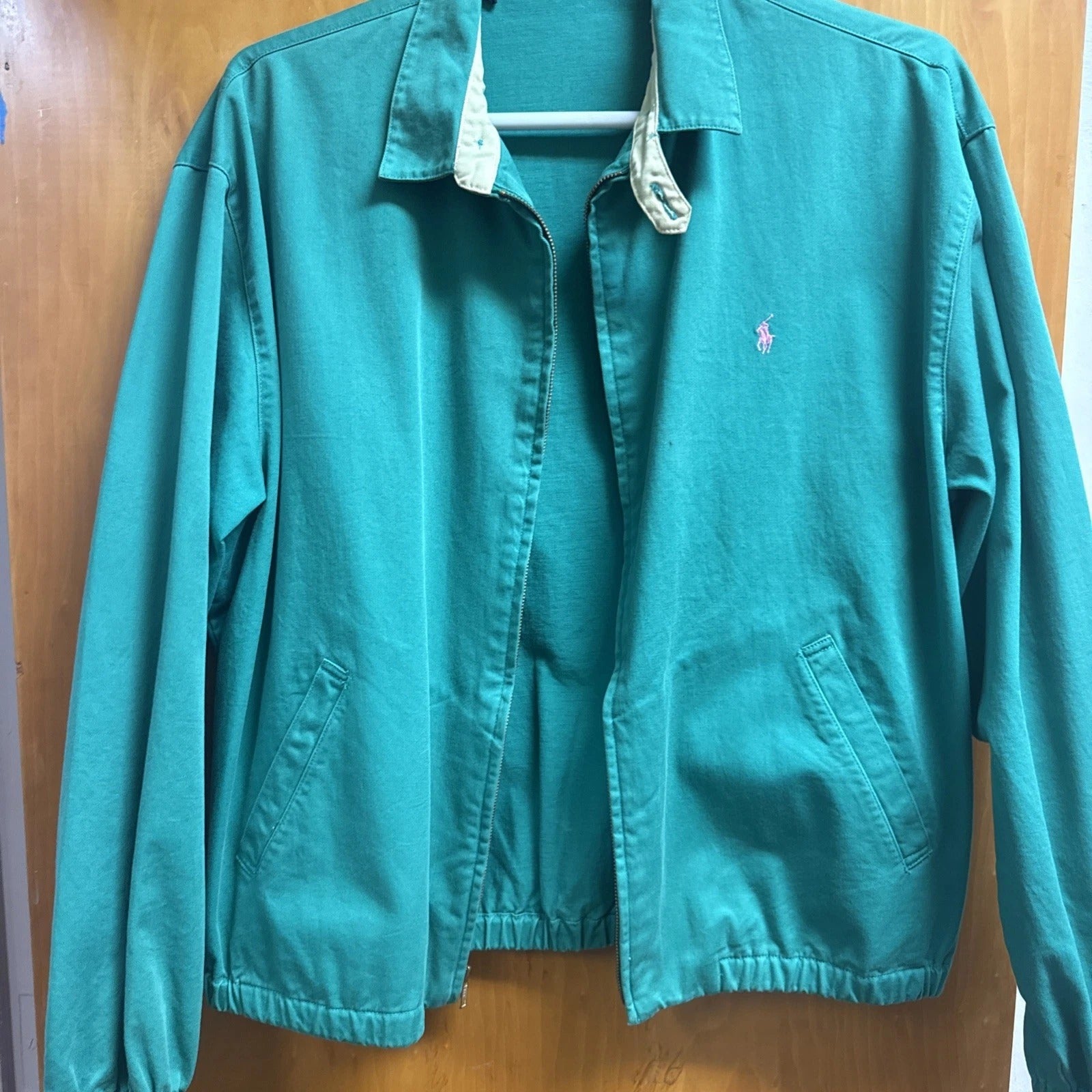 Teal jacket with a brand logo on a wooden surface