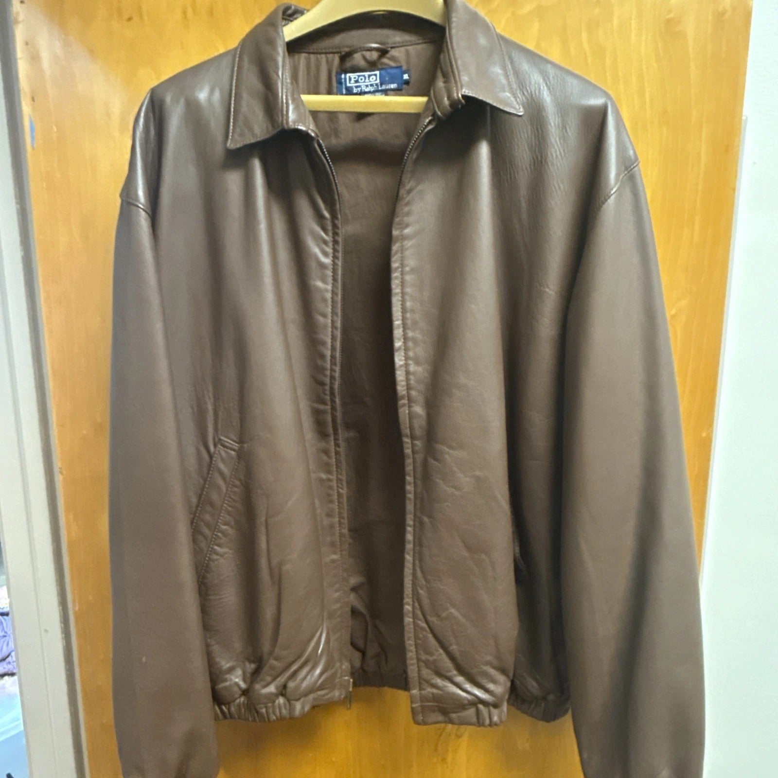 Brown leather jacket hanging on a wooden door