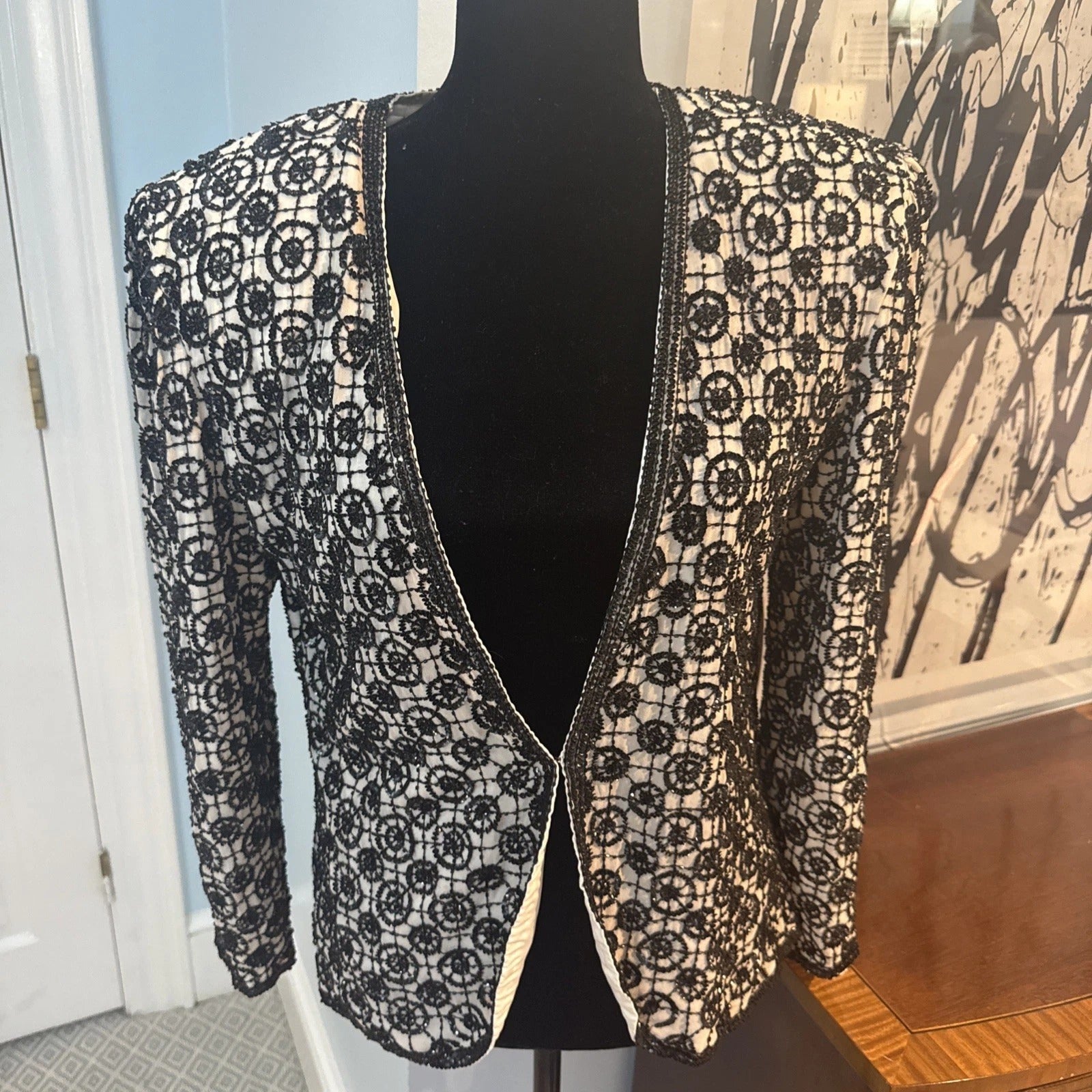 Black lace cardigan on a mannequin against a neutral background