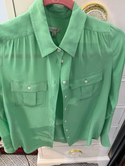 Green shirt on a hanger against a white wall