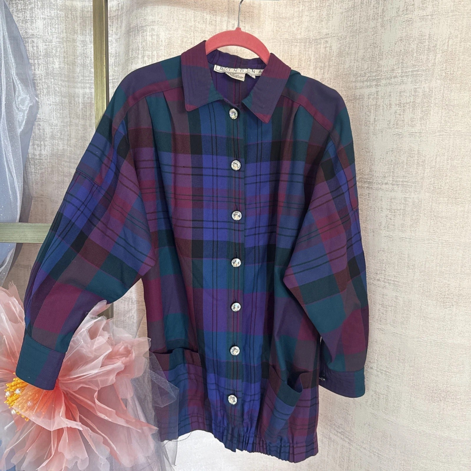 Plaid shirt on a hanger against a neutral background
